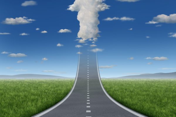 No limits success concept with a road or highway going forward fading into the sky with a group of clouds shaped as an upward arrow as a business symbol of financial freedom and aspirations.