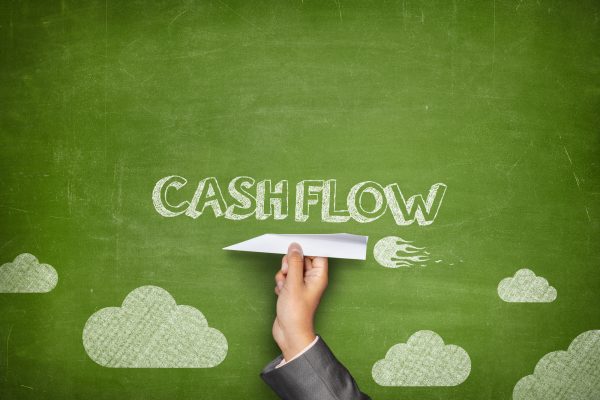 Cash flow concept on green blackboard with businessman hand holding paper plane