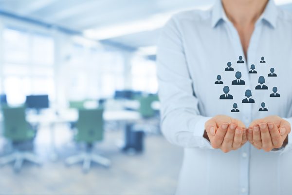 Customer care, care for employees, life insurance and marketing segmentation concepts. Protecting gesture of businesswoman or personnel and icons representing group of people. Wide banner composition wit office in background.